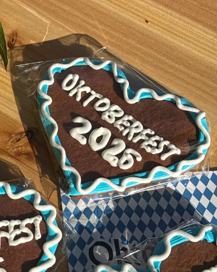 Close-up of an Oktoberfest gingerbread heart with white lettering and a blue-and-white piped border