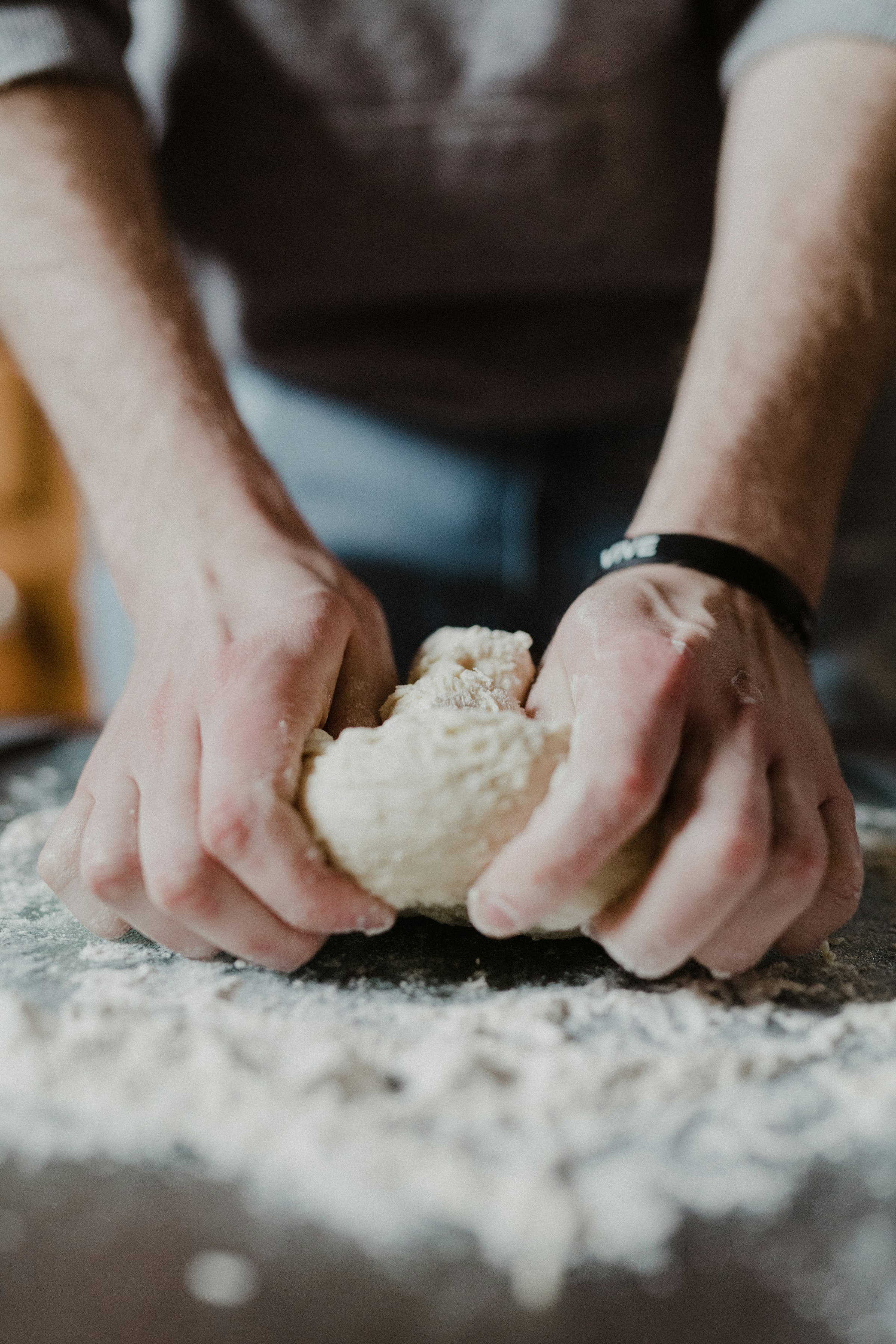 A baker's hands shaping pastry dough on a wooden table